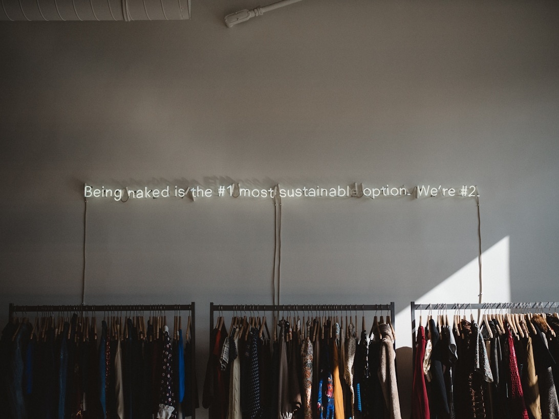 Interiör från en klädbutik med texten 'Att vara naken är det mest hållbara alternativet. Vi är #2.' på väggen.