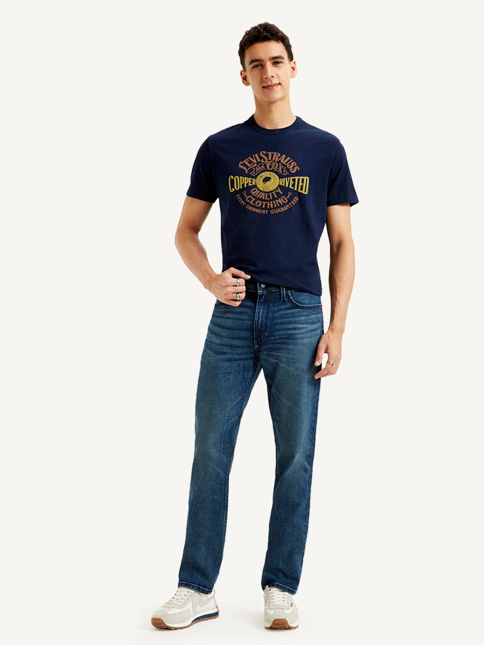 Man i en marinblå t-shirt med en klassisk logotyp som representerar ett hållbart och tidlöst plagg.